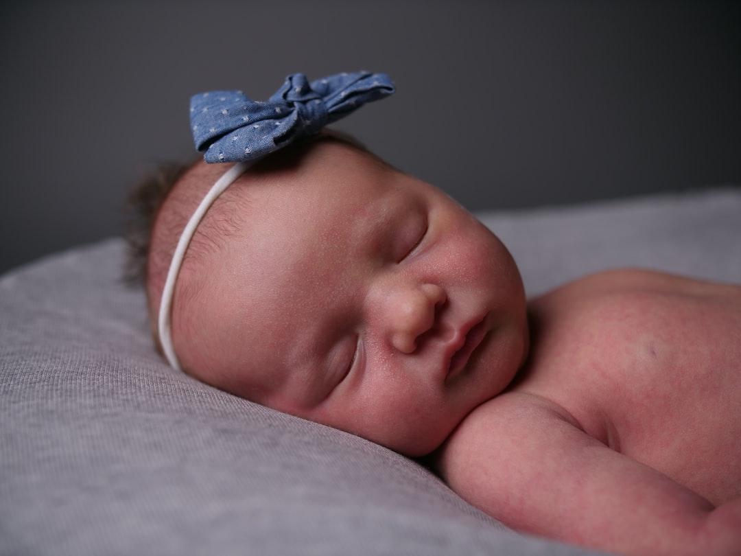 baby in pink headband lying on bed