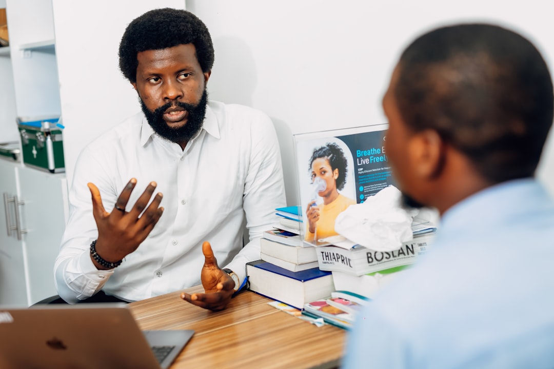 A man sitting at a desk talking to another man