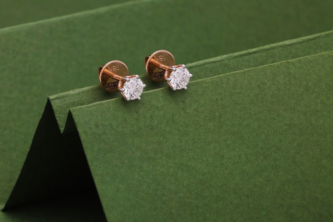 Two small diamond stud earrings on green background